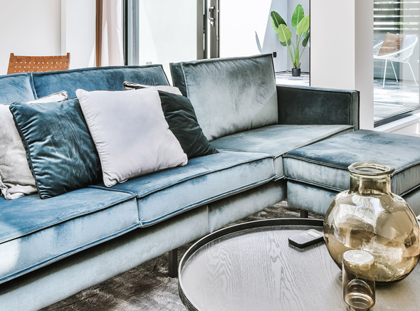 modern blue sofa with decorative pillows and glass table in stylish living room
