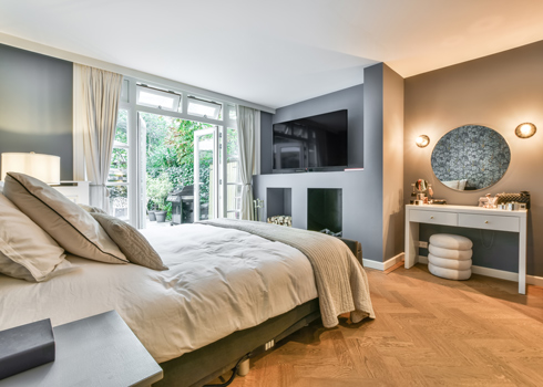modern bedroom with natural light and stylish decor featuring a large bed and a vanity table offering a cozy retreat for three occupants