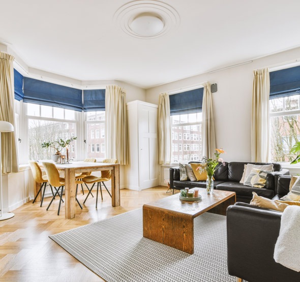 modern living room with large windows and wooden furniture featuring a black leather sofa dining table and floral decorations inviting ambiance and home decor ideas