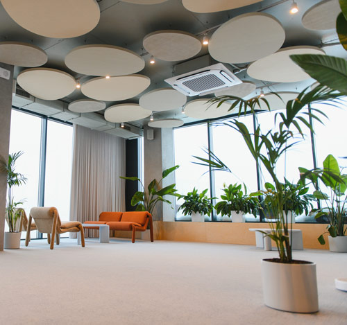 Spacious office interior with plants, modern furniture, and natural light.