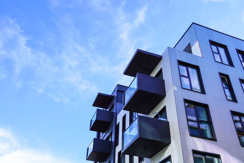 Modern residential building exterior with balconies and clear blue sky.