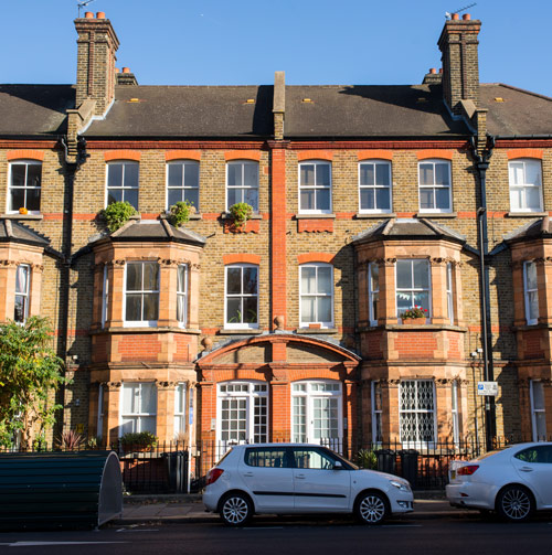 Victorian-style residential building in West London with parked cars and greenery.