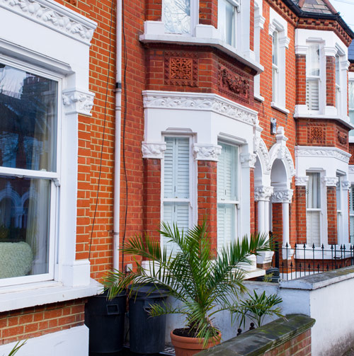 Victorian-style residential buildings with decorative brickwork and a potted palm in West London.
